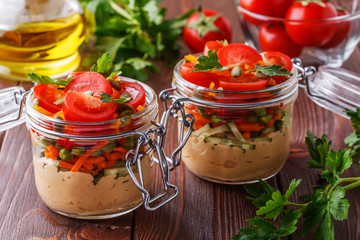 Healthy breakfast - hummus with vegetables in glass jars.