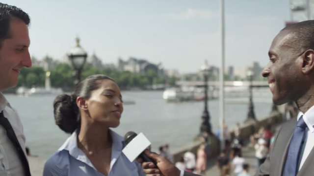  News reporter interviewing 2 business people in London on a hot summer day