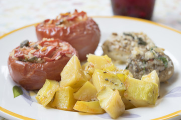 baked potatoes in a dish with stuffed tomatoes and mushrooms