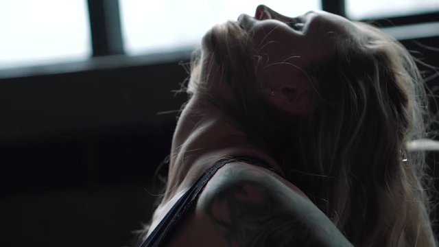 Blonde woman in bodysuit with perfect body standing in studio with sexy buttocks