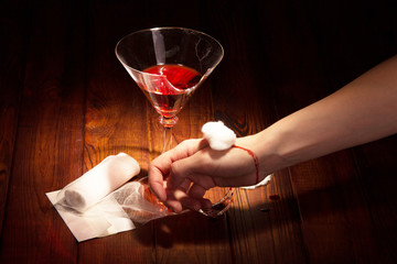 Broken glass and bloody hand closeup on dark
