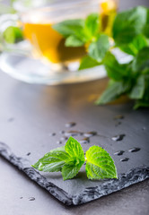 Mint leaf. Mint leaves. Tea. Mint Tea. Herbal tea. Tea in a glass cup, mint leaves, dried tea, sliced lime. herbs tea and mint leaves on a slate plate in a restaurant or teahouse tea room.