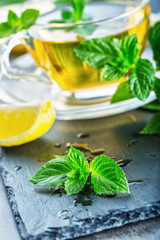 Mint leaf. Mint leaves. Tea. Mint Tea. Herbal tea. Tea in a glass cup, mint leaves, dried tea, sliced lime. herbs tea and mint leaves on a slate plate in a restaurant or teahouse tea room.