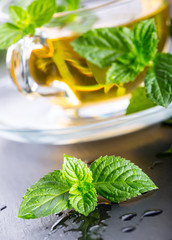 Mint leaf. Mint leaves. Tea. Mint Tea. Herbal tea. Tea in a glass cup, mint leaves, dried tea, sliced lime. herbs tea and mint leaves on a slate plate in a restaurant or teahouse tea room.