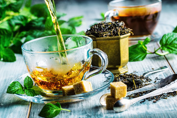 Tea. Mint Tea. Herbal tea. Mint leaf. Mint leaves. Tea in a glass cup, mint leaves, dried tea, sliced lime. herbs tea and mint leaves on a slate plate in a restaurant or teahouse tea room. - obrazy, fototapety, plakaty