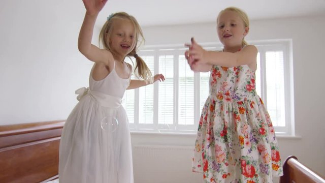  2 Little girls having fun at home, jumping up and down on the bed