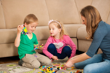 Naklejka premium Dzieci i ich mama bawią się klockami na ziemi