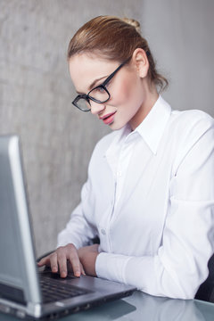 Blonde caucasian businesswoman typing on tablet