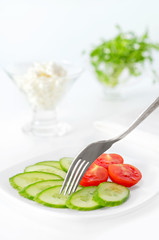 Sliced tomato and cucumber on a plate.