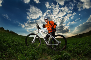 Man Cyclist with bike on sunset