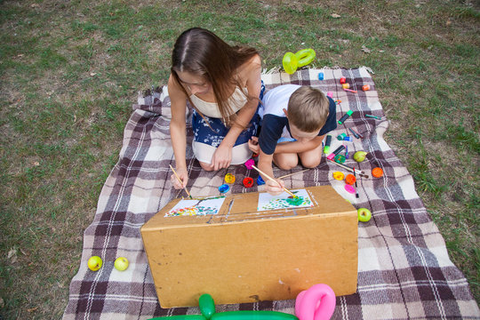 Older sister trying to teach her brother to paint in the park