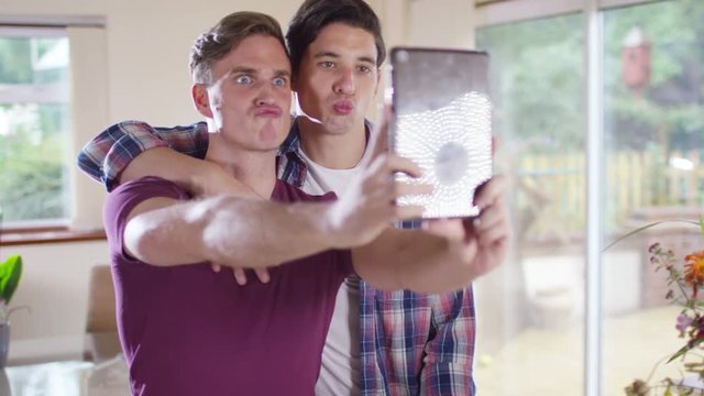  Young gay couple pulling faces & taking a selfie with computer tablet