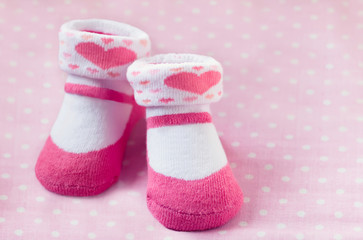 Pair of pink child socks closeup on spotted pink background, selective focus