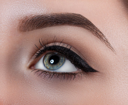 Female eye close-up. Macro. Perfect makeup and eyebrows. Beautiful gray eyes