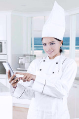 Pretty female chef uses smartphone in kitchen