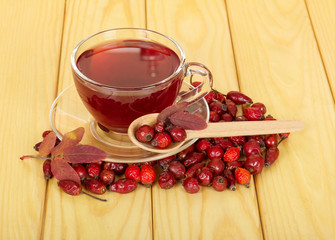 Glass Cup with rose hips on wooden background
