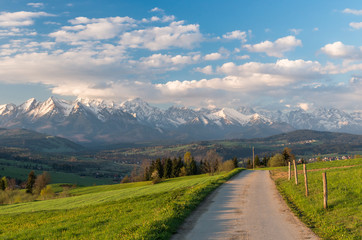 Beautiful spring panorama of Tatra mountains and country road in the green field