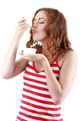 Young female enjoying taste of yogurt isolated on white