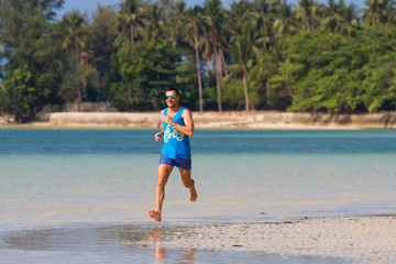 Fototapeta na wymiar The man runs, runs on the beach, in the tropical country plays sports