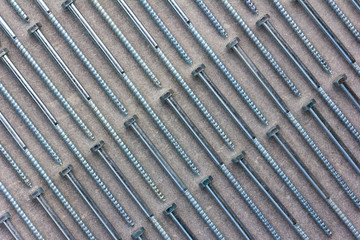 set of new metal screws on a grey background are on the diagonal. Flat lay, top view