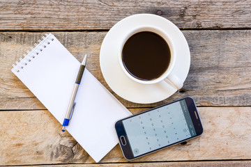 cup of coffee and smartphone with paper note on wood table backg