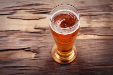 Glass of light beer on wooden background. Retro stylization