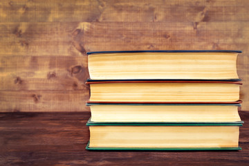 Books on wooden table on wooden wall background