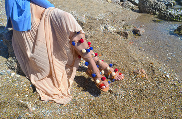 woman advertises traditional greek sandals gladiator on beach