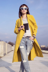 Young woman in a yellow coat on a background of city