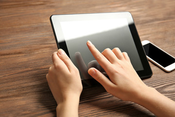 Mobile phone and female hands using tablet, on the wooden background