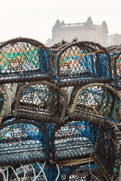 Stacked lobster pots in the harbour. Scarborough Grand Hotel, out of focus, behind. HDR image. In Scarborough, England. On 5th May 2016.