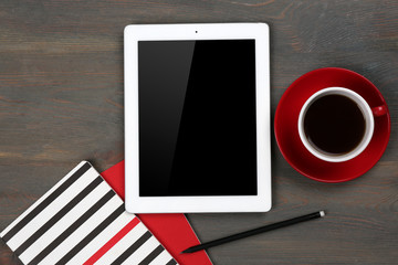 Digital tablet with cup of coffee and notebook on wooden table, closeup