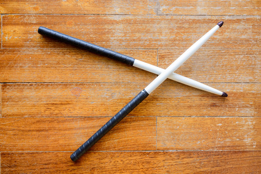 Size 5A hickory drumsticks painted white with black teardrop shaped tips and wrapped with tennis overgrip tape.