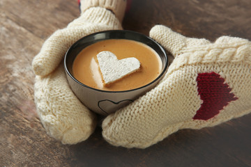 Woman hands in mittens holding a cup of coffee