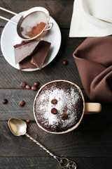 Chocolate fondant cake in cup on wooden background
