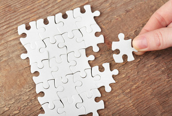 Woman playing with jigsaw puzzle on wooden table