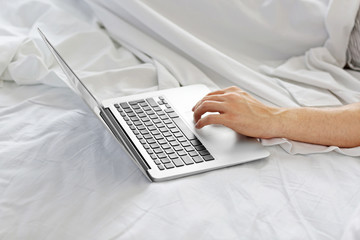 Man lying in bed with his laptop