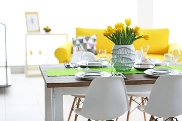 Dining room interior with sofa and table served for dinner