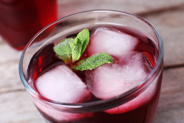 Glass of cherry soda with ice and fresh mint on rustic wooden background