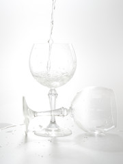 Water pouring from bottle into the glass, isolated on white