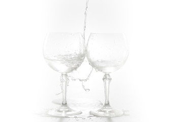 Water pouring from bottle into the glass, isolated on white