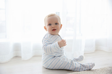 Fototapeta premium Adorable baby boy sitting on the floor, close up