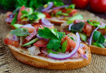Sandwiches with greens, tomatoes, meat, salami on crispy bread on the table