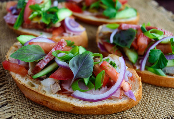 Sandwiches with greens, tomatoes, meat, salami on crispy bread on the table