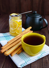 Crispy bread sticks and tea with lemon on wooden background. Breakfast