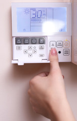 Woman switching a digital thermostat