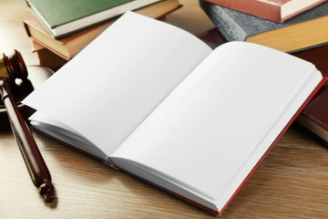 Wooden gavel and open book on wooden background