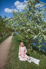 beautiful girl in dress sitting under the apple blossom