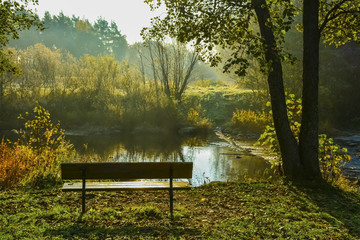 Park bench and river in autumn 