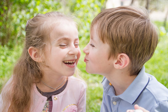 Boy trying kissing cheerful girl outdoor